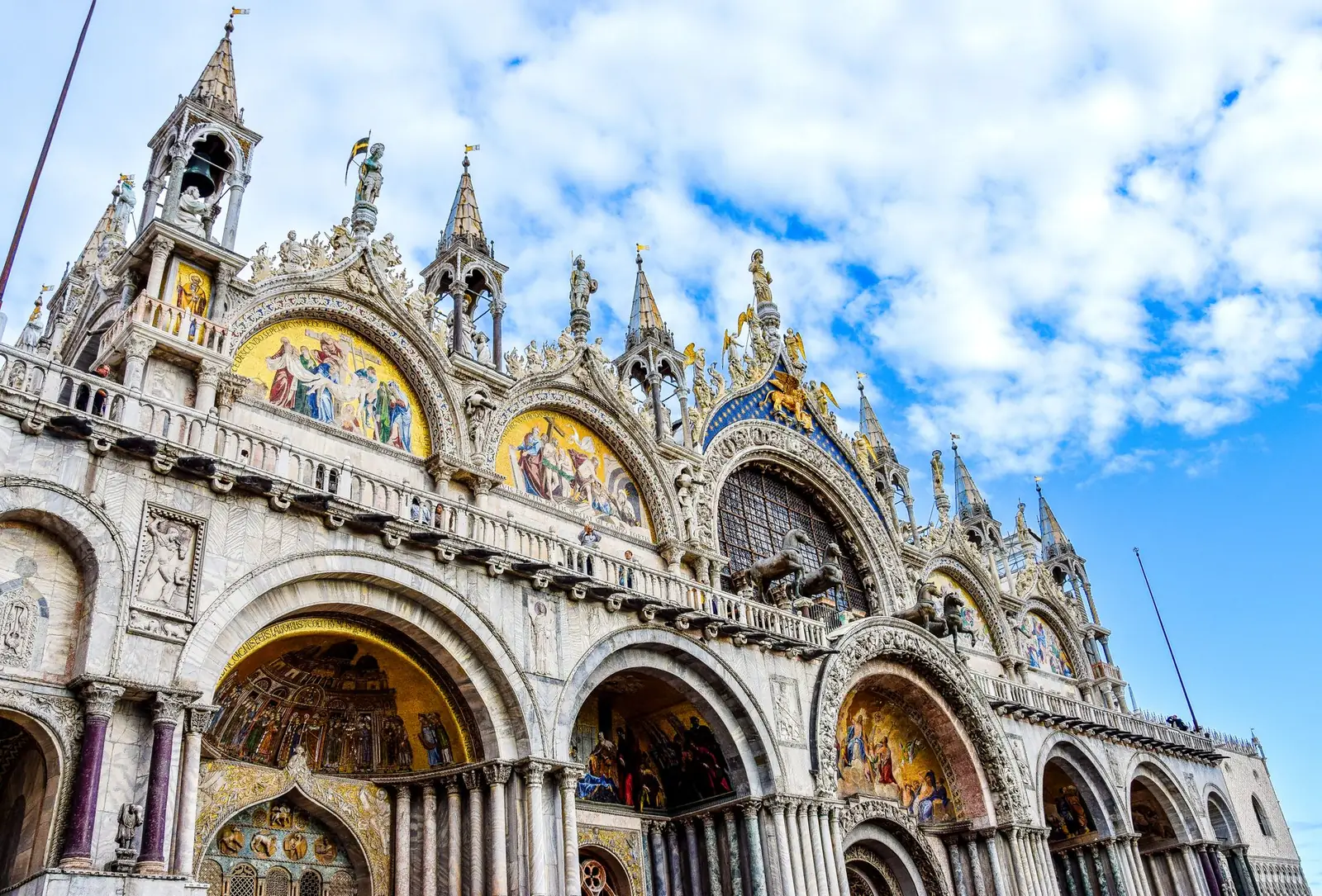 Angled exterior view of St Mark’s Basilica, its domes and sculpted facade in Venice.